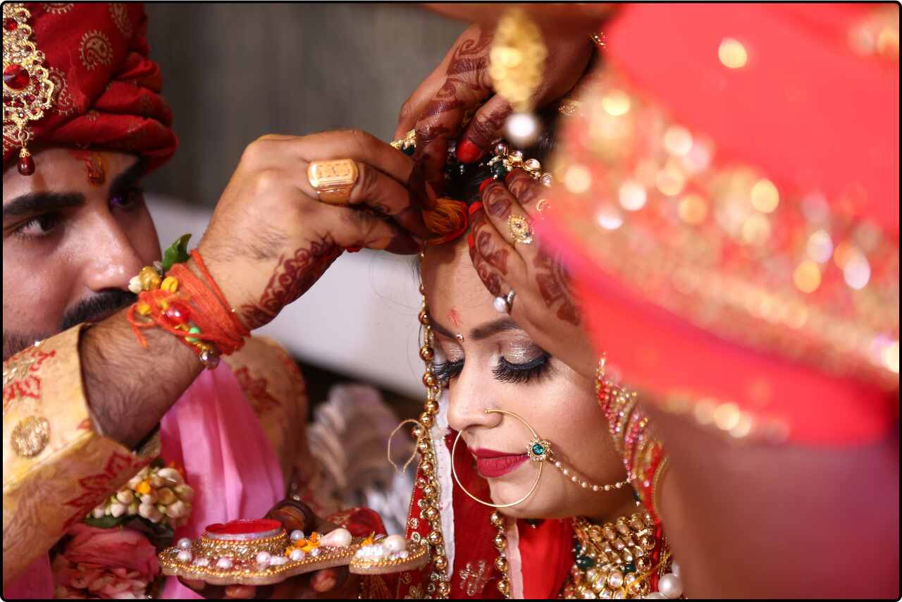 Close-up of the bride’s forehead being adorned with sindur during a traditional Indian wedding ceremony.